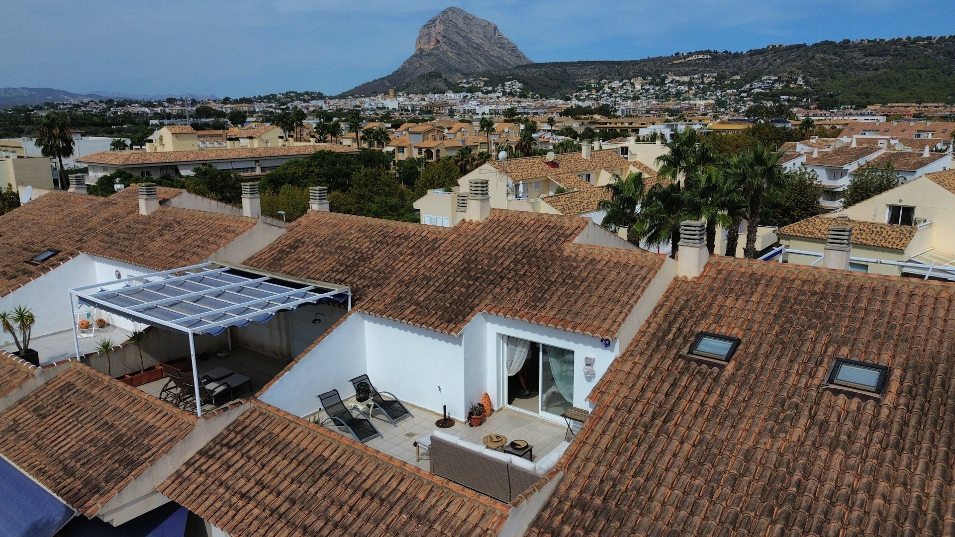 Luchtfoto van het solariumterras met luifel en tuinmeubilair, omgeven door pannendaken.