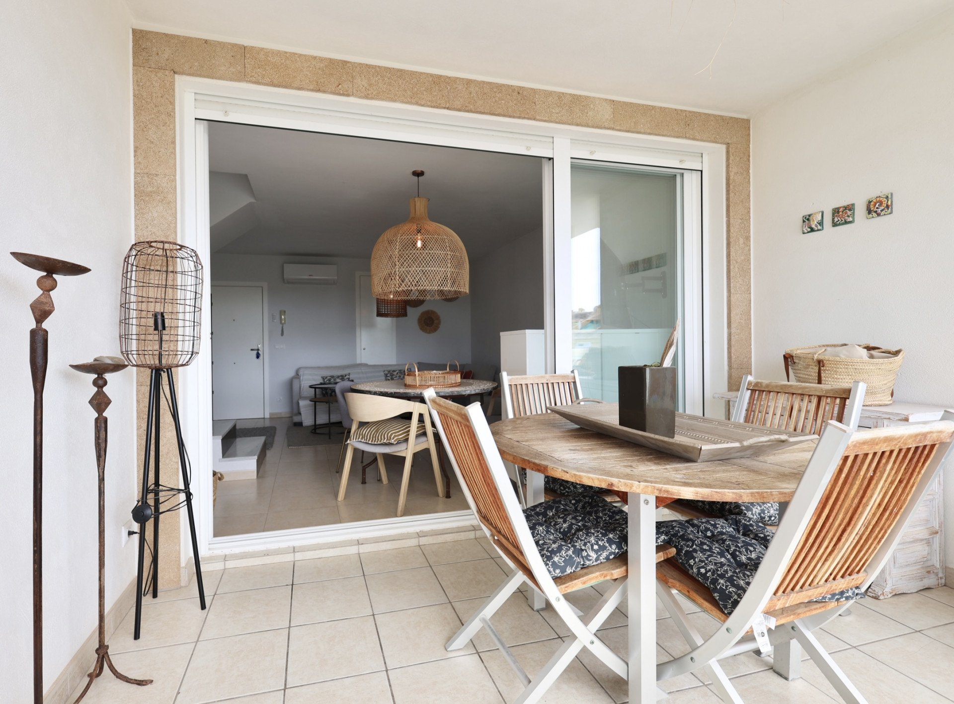 Overdekt terras met houten tafel en opklapbare stoelen met kussens met patroon.