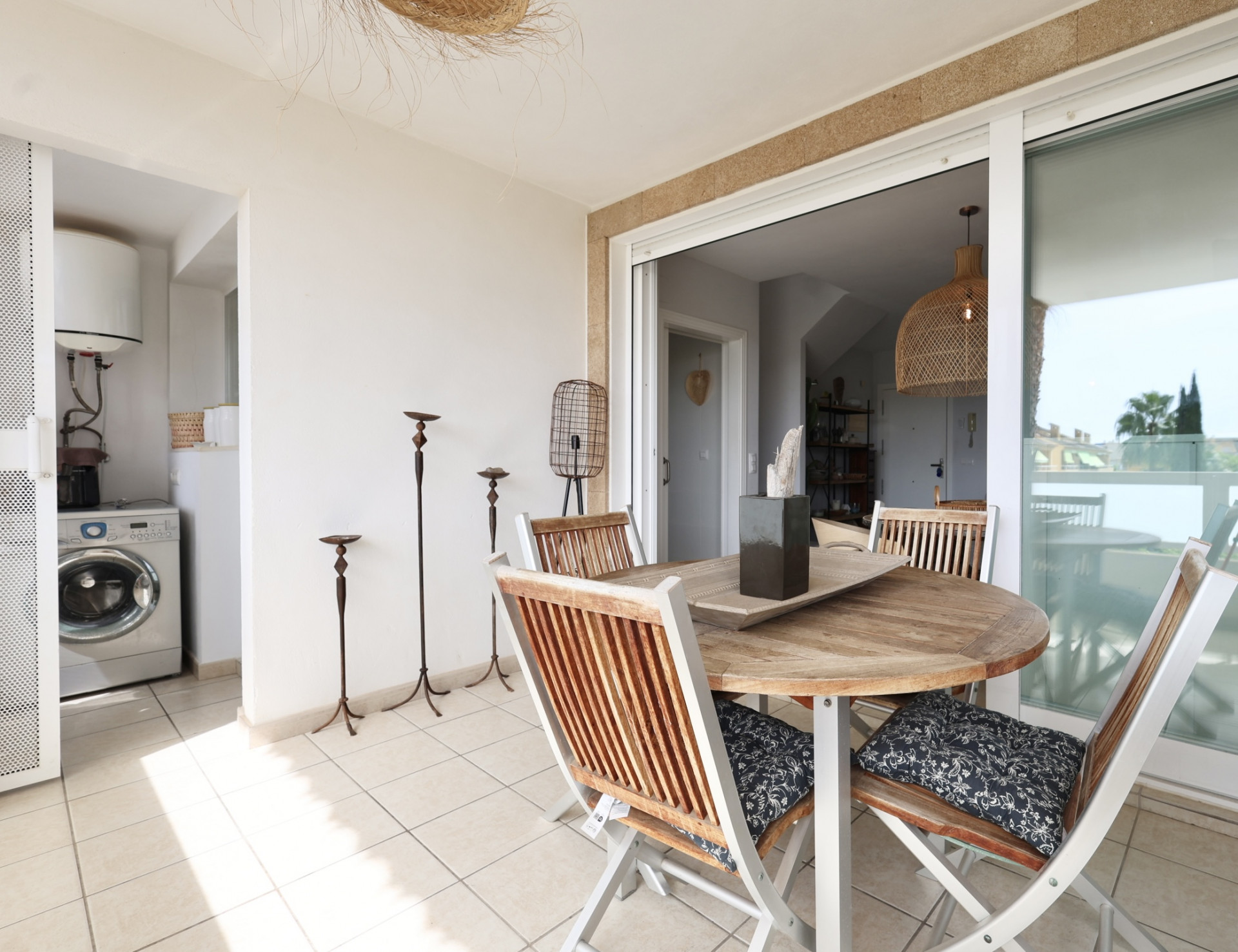 Terras met ronde houten tafel en bijpassende stoelen, met toegang tot een wasruimte.