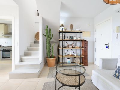 Licht interieur met witte trap, houten en metalen rek, en een rotan salontafel.