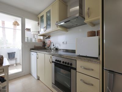 Lichte keuken met granieten aanrechtblad, roestvrijstalen apparaten en toegang tot balkon.