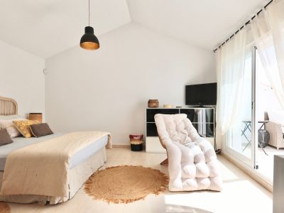 Lichte slaapkamer met rotan bed, jute vloerkleed en toegang tot het terras.