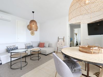 Lichte woon-eetkamer met hoekbank, rieten lampen en een design salontafel.