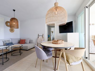 Lichte woon-eetkamer met rieten lampen en toegang tot het terras.