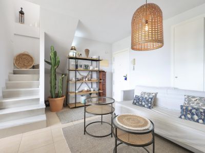 Lichte woonkamer met trap naar de duplex, minimalistische inrichting en een hanglamp van wicker.