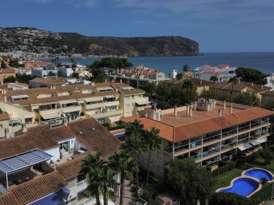 Luchtfoto van de urbanisatie met zwembad en woongebouwen met rode daken nabij de kust van Jávea.