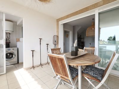 Terras met ronde houten tafel en bijpassende stoelen, met toegang tot een wasruimte.