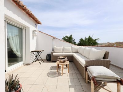 Zonnig terras met rotan meubilair en gedeeltelijk uitzicht op de horizon.