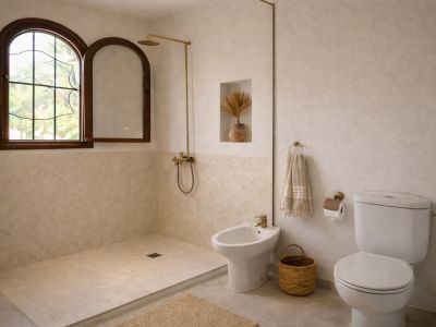 Lichte badkamer met inloopdouche, beige mozaïektegels en een gewelfd houten raam. Messing kranen en gestructureerde muren aanwezig.