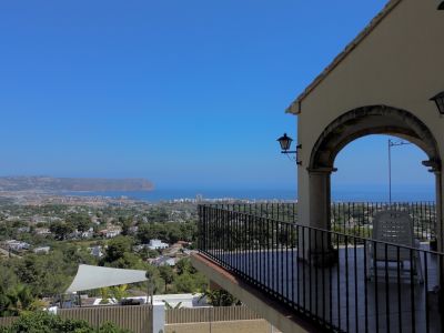 Overdekt terras met panoramisch zee-, stads- en landschapszicht, omlijst door een stenen boog en smeedijzeren balustrade.