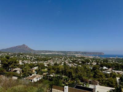 Panoramisch uitzicht op Jávea met de imposante Montgó, de Middellandse Zee en het groene, beboste stadslandschap onder een heldere lucht.