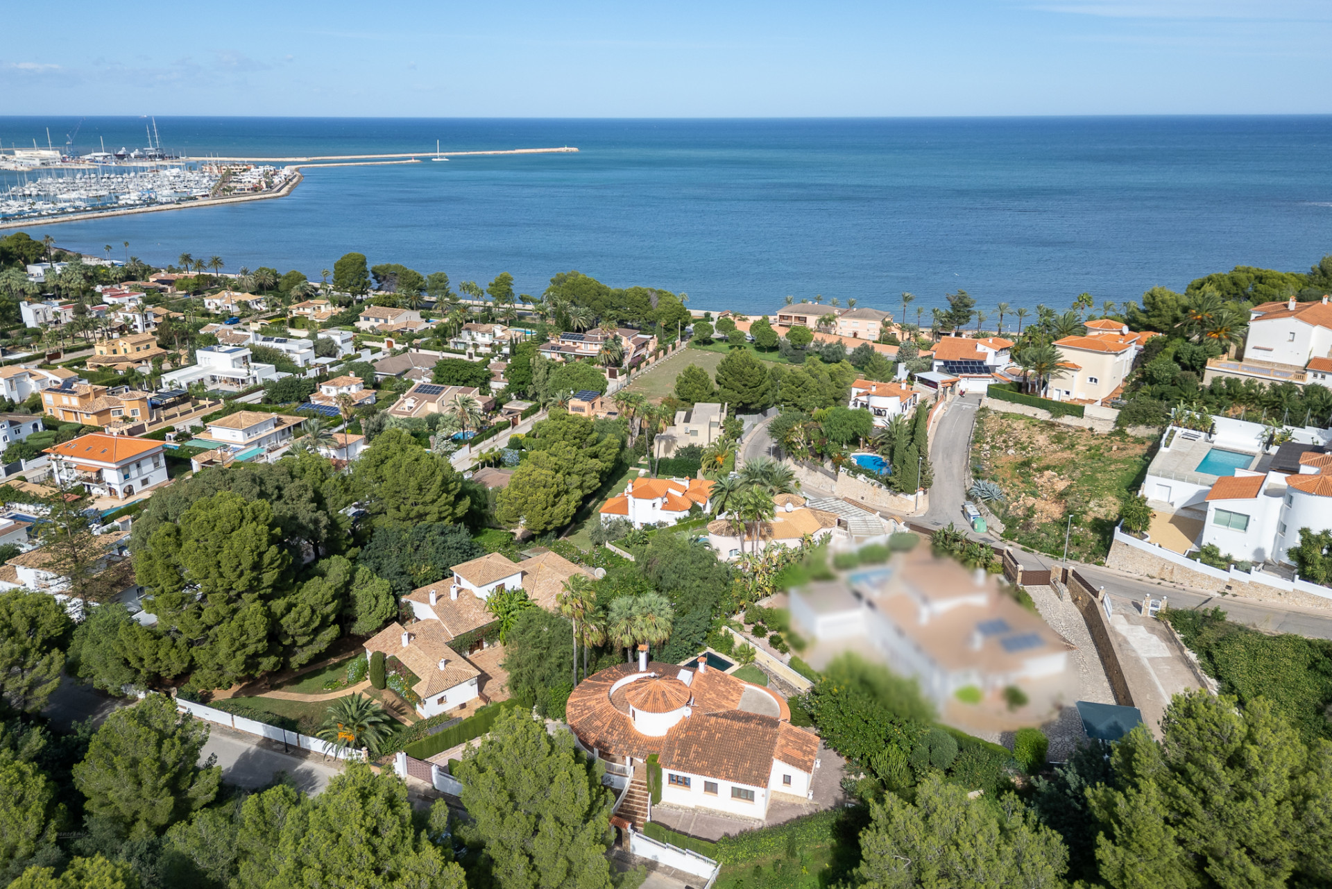 Luchtfoto van de residentiële wijk van Dénia, met villa's, weelderig groen en de jachthaven aan de Middellandse Zee.