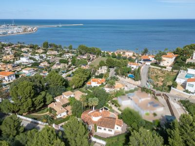 Luchtfoto van de residentiële wijk van Dénia, met villa's, weelderig groen en de jachthaven aan de Middellandse Zee.