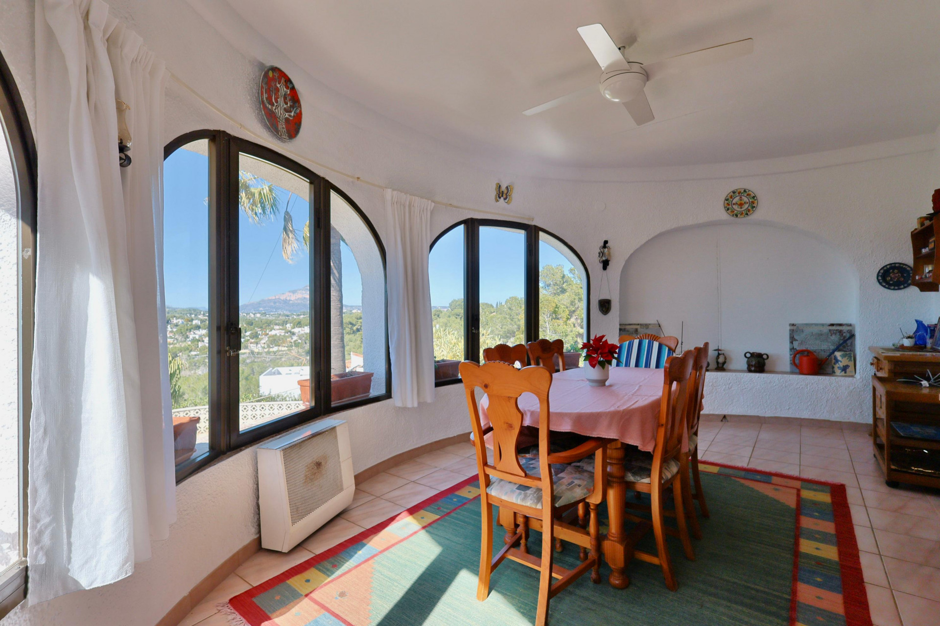 Lichte eetkamer met gewelfde ramen en panoramisch uitzicht op het landschap van Jávea.