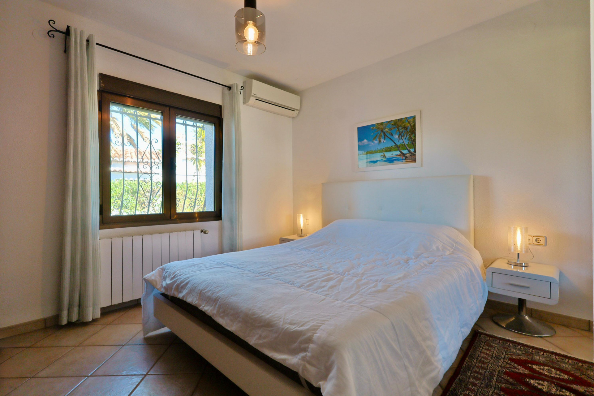 Lichte slaapkamer met tweepersoonsbed, moderne nachtkastjes en een raam met uitzicht naar buiten.