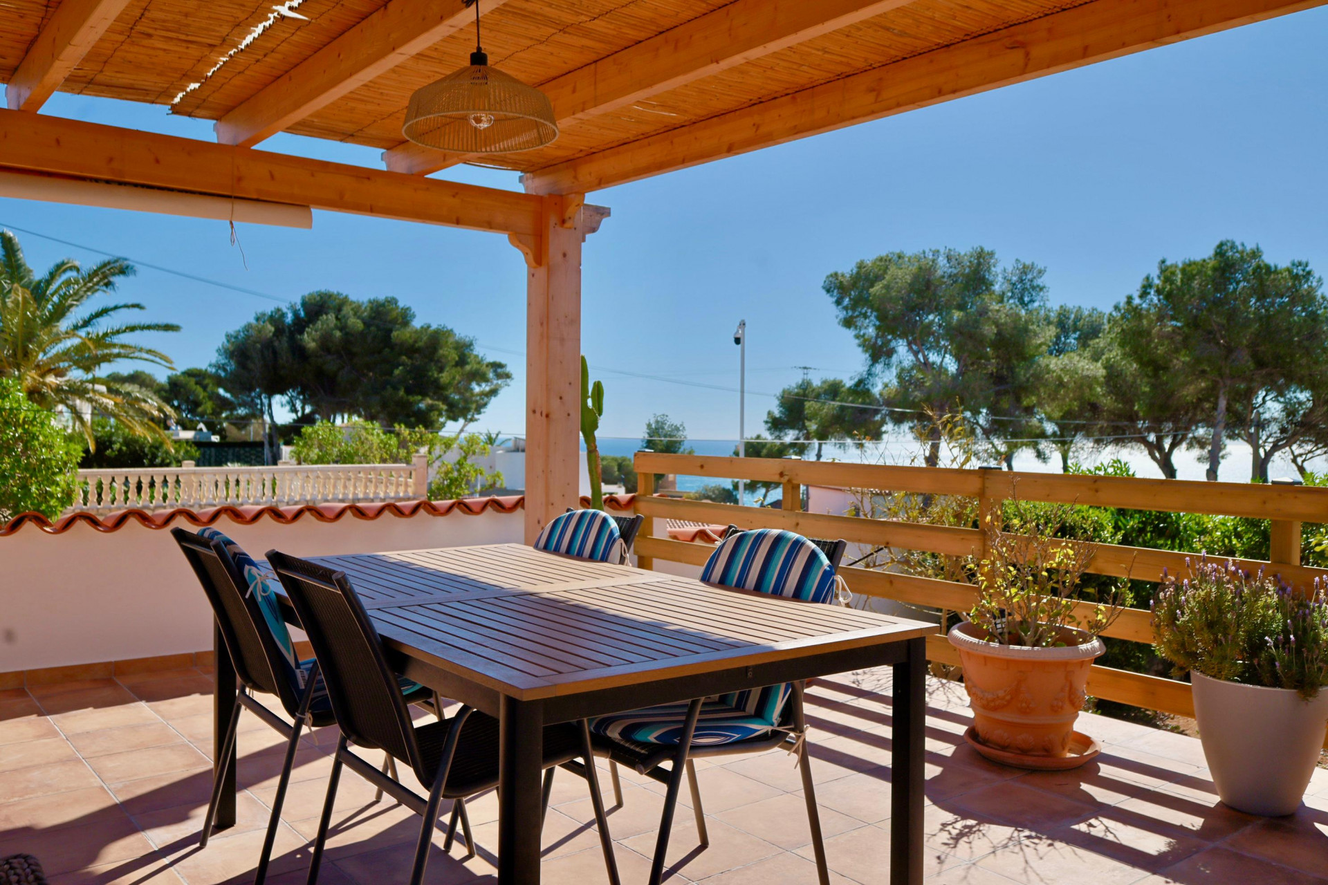 Overdekt terras met eettafel en uitzicht op de Middellandse Zee.