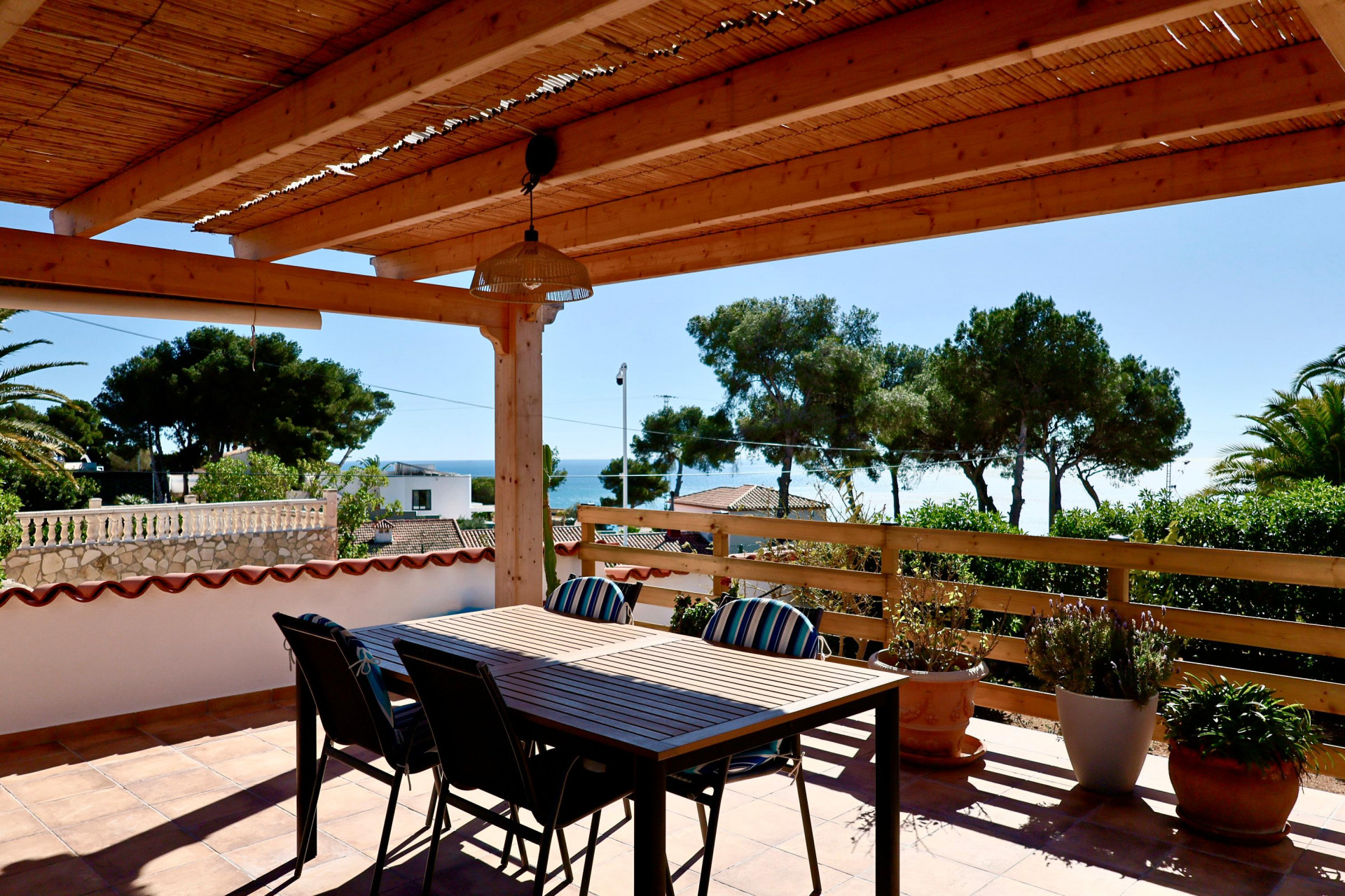 Overdekt terras met eettafel en uitzicht op zee in Jávea.