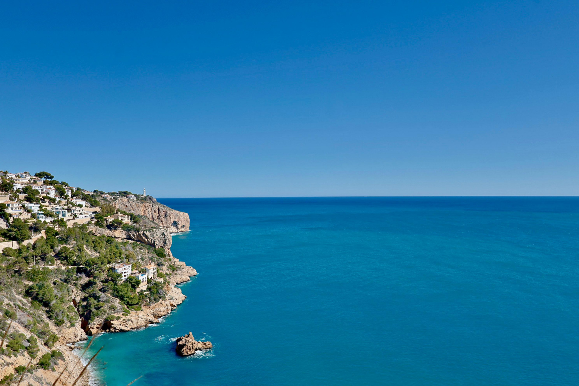 Panoramisch uitzicht op de rotsachtige kustlijn van Jávea en de blauwe Middellandse Zee.