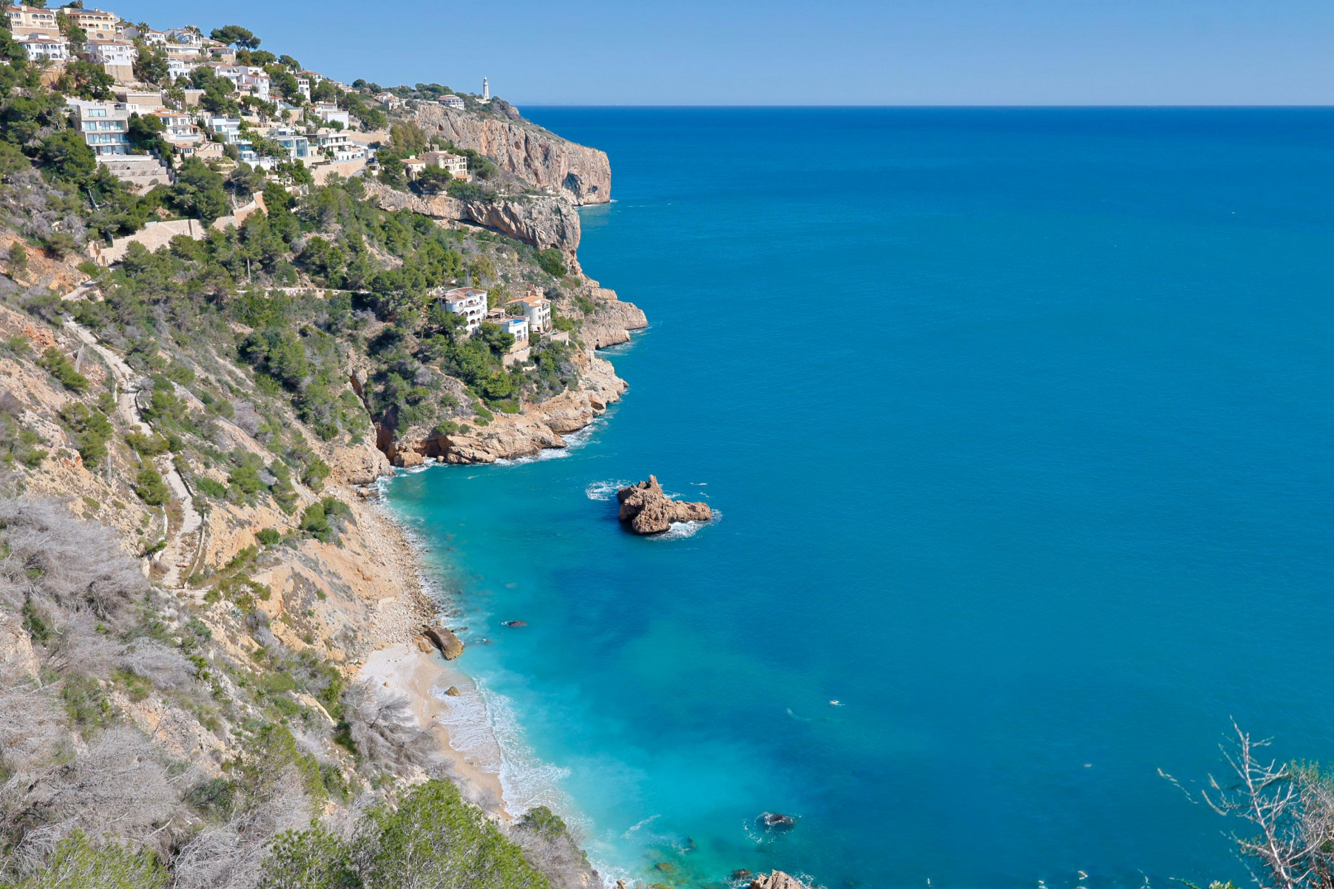 Panoramisch uitzicht op de rotsachtige kustlijn van Jávea en het turquoise water.