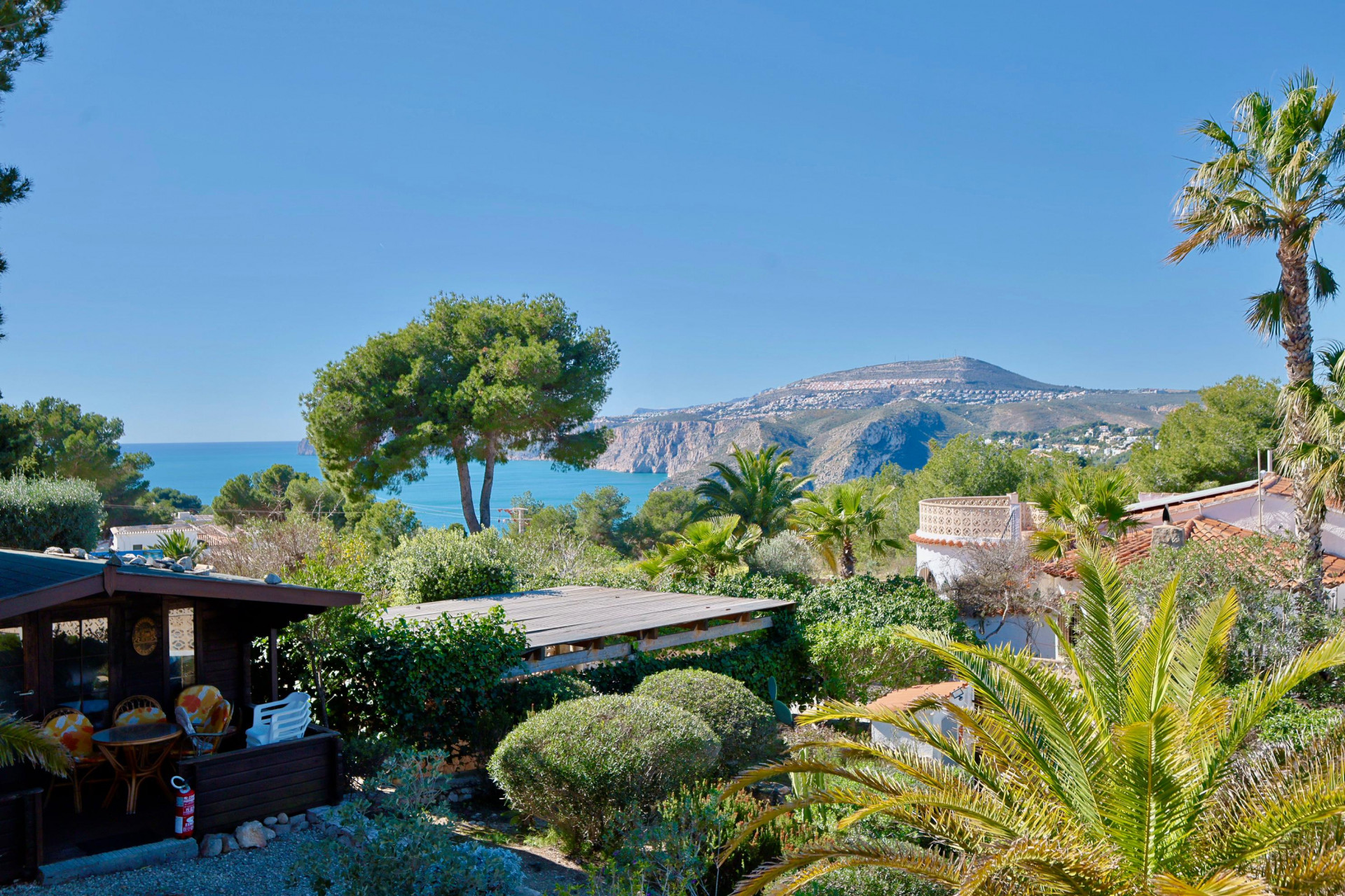 Panoramisch uitzicht op Jávea met houten hut en weelderig groen.