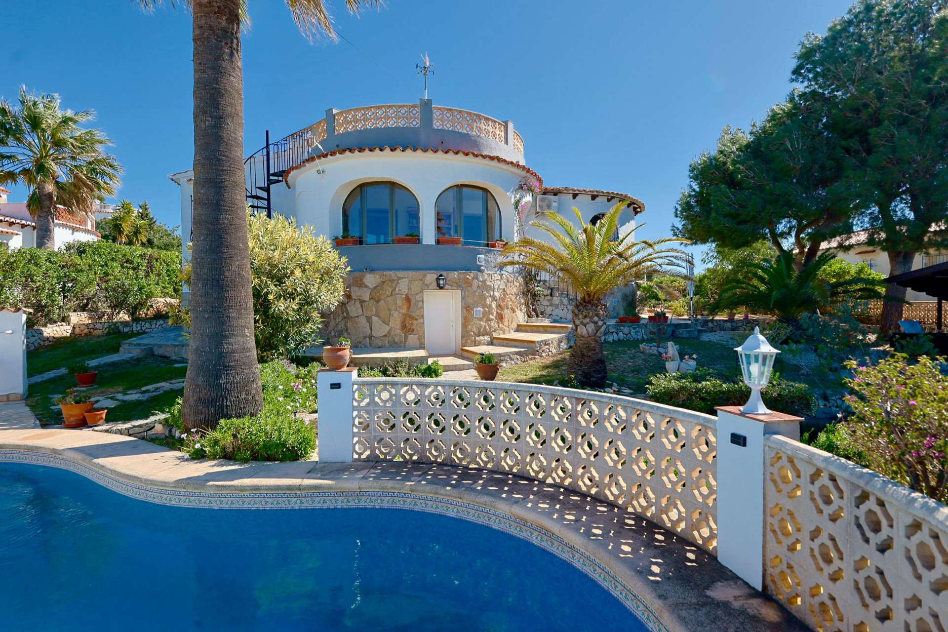 Zwembadzicht met traliewerk en stenen gevel van de villa in Jávea.