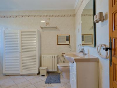 Betegelde badkamer met witte kast met lamellen en een beige wastafel.