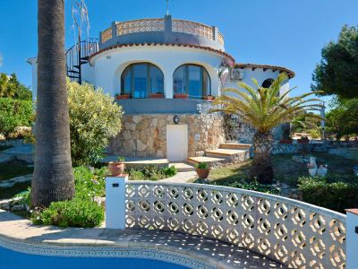 Buitenaanzicht van de villa met zwembad en stenen gevel, omgeven door mediterrane tuinen.