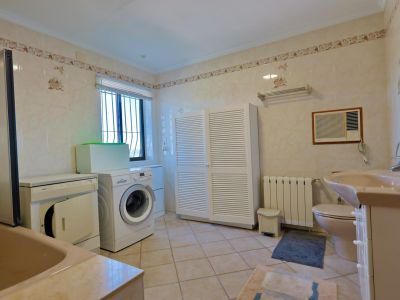 Functionele badkamer met wasmachine, droger en ruime witte kast met lamellen.