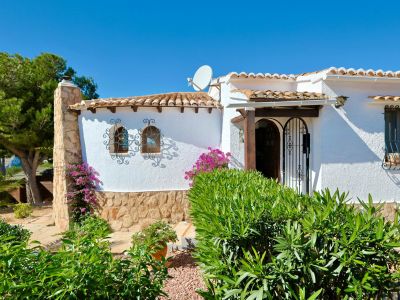 Gevel van een mediterrane villa met stenen details, dakpannen en sierlijk smeedwerk.