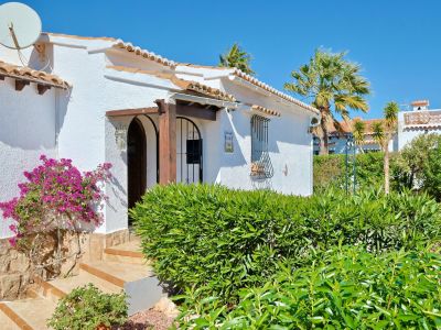 Gevel van mediterrane villa met bougainville en houten boogingang.