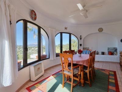 Lichte eetkamer met gewelfde ramen en panoramisch uitzicht op het landschap van Jávea.