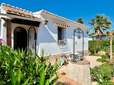 Mediterrane villa gevel met decoratieve waterput en weelderige tuin.