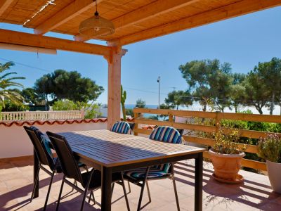 Overdekt terras met eettafel en uitzicht op de Middellandse Zee.
