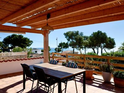 Overdekt terras met eettafel en uitzicht op zee in Jávea.