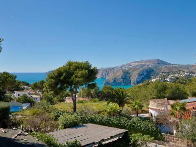 Panoramisch uitzicht op de kust en bergen van Jávea vanaf het terras, met mediterrane vegetatie.