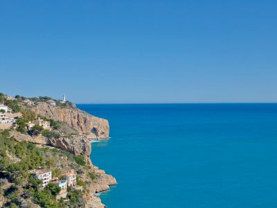 Panoramisch uitzicht op de rotsachtige kustlijn en de Middellandse Zee vanuit Jávea, met witte huizen op de heuvel.
