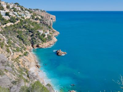 Panoramisch uitzicht op de rotsachtige kustlijn van Jávea en het turquoise water.