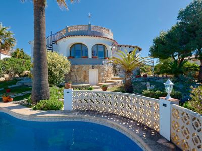 Zwembadzicht met traliewerk en stenen gevel van de villa in Jávea.