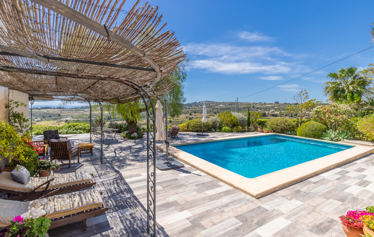 Buitenzwembad met een terras van antisliptegels en een rustieke pergola van smeedijzer en riet. Biedt panoramisch uitzicht over de vallei en de volgroeide mediterrane tuin.