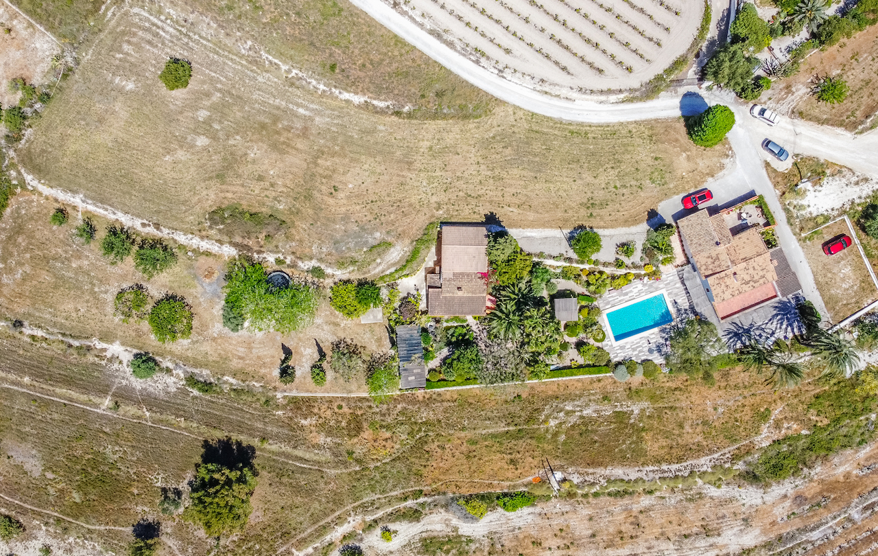 Luchtfoto van het landgoed met de indeling van de twee woningen, het zwembad met terras en de volgroeide tuinen in het landelijke landschap.