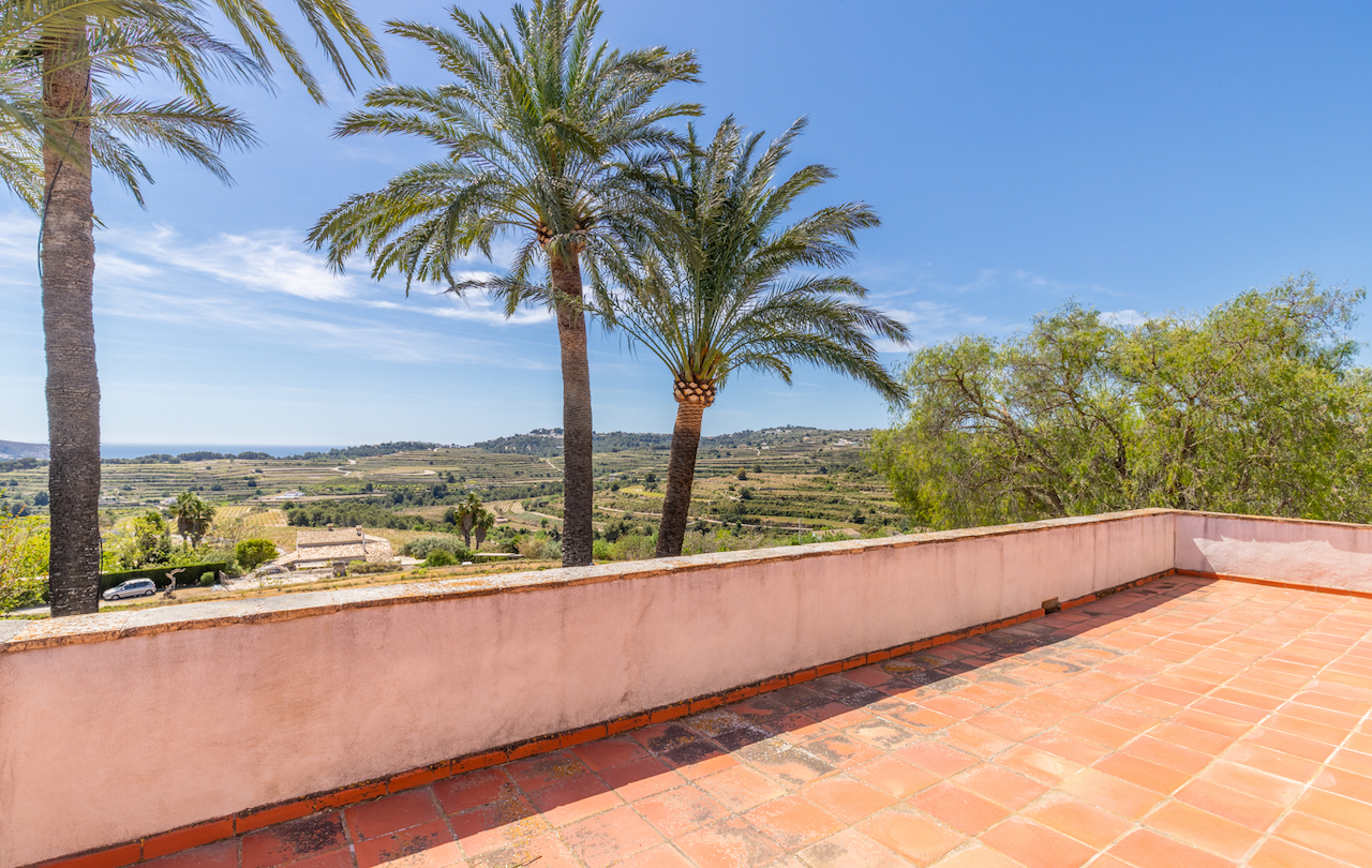 Verhoogd terras met traditionele terracotta tegels, met panoramisch uitzicht over de terrasvormige wijngaarden en de Middellandse Zee in de verte.