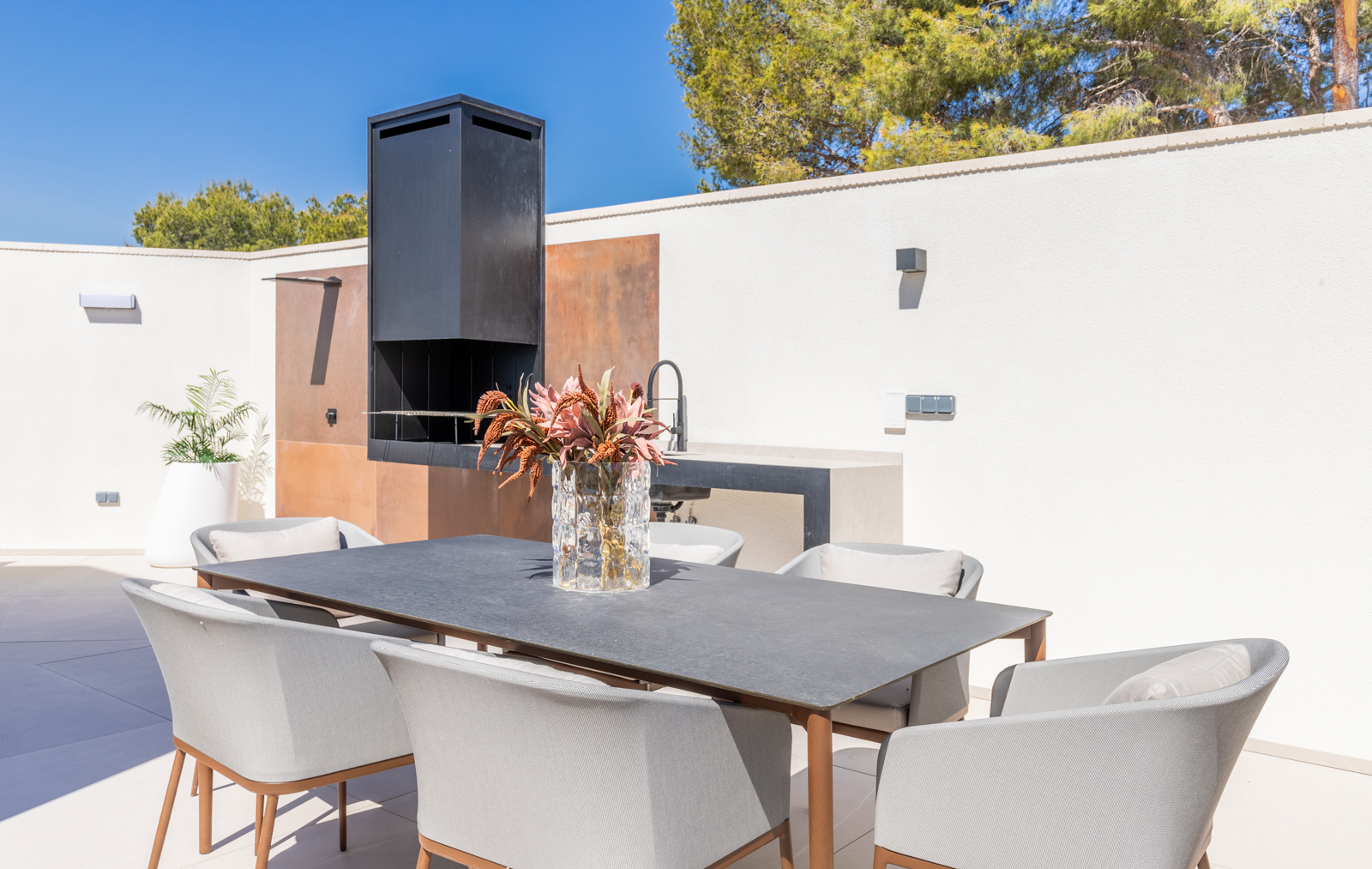 Detail van de buitenbarbecue met eettafel en grijze stoelen in La Nucia.
