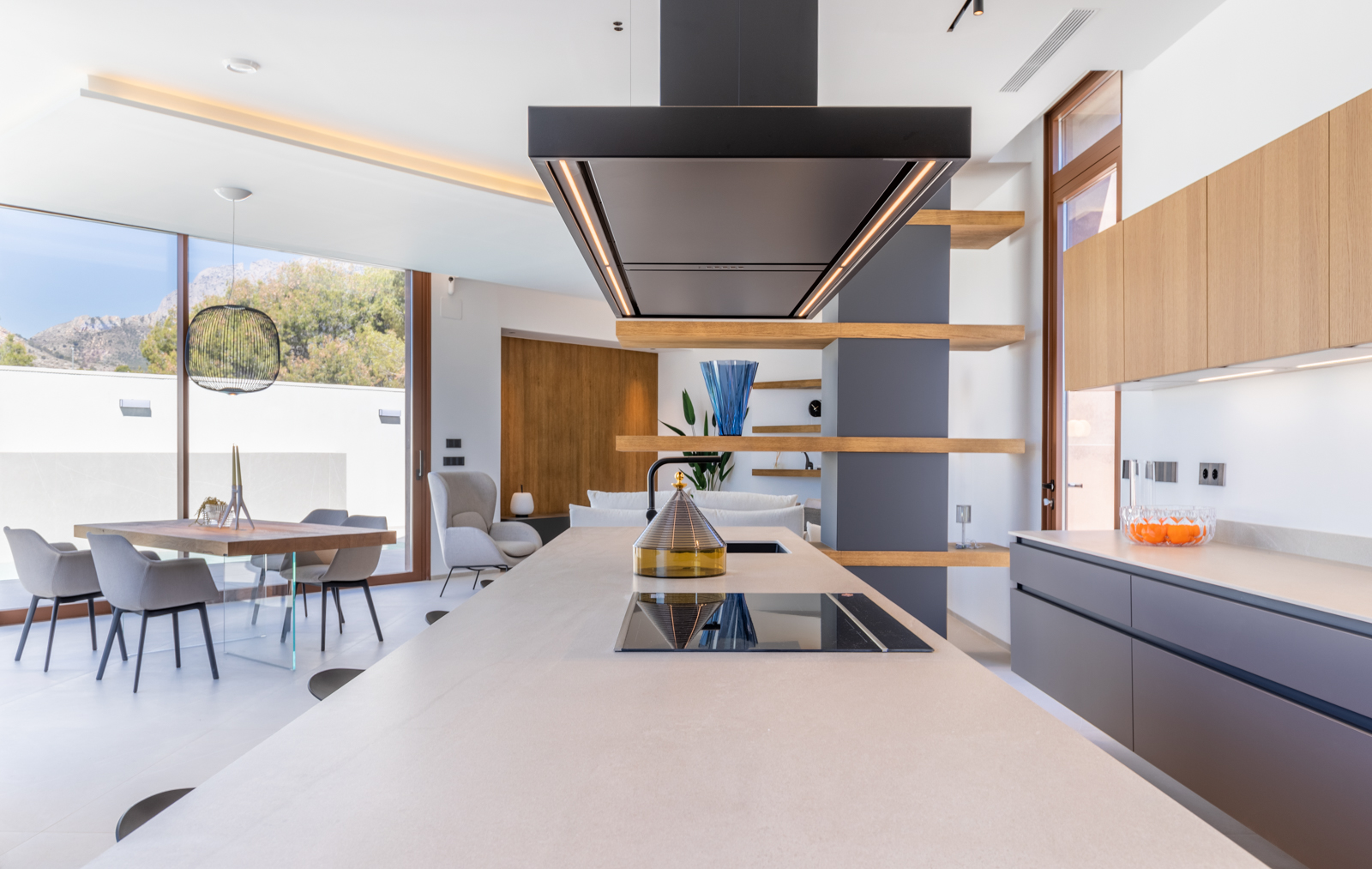 Detail van de moderne keuken met centraal eiland, zwarte afzuigkap en open houten schappen.