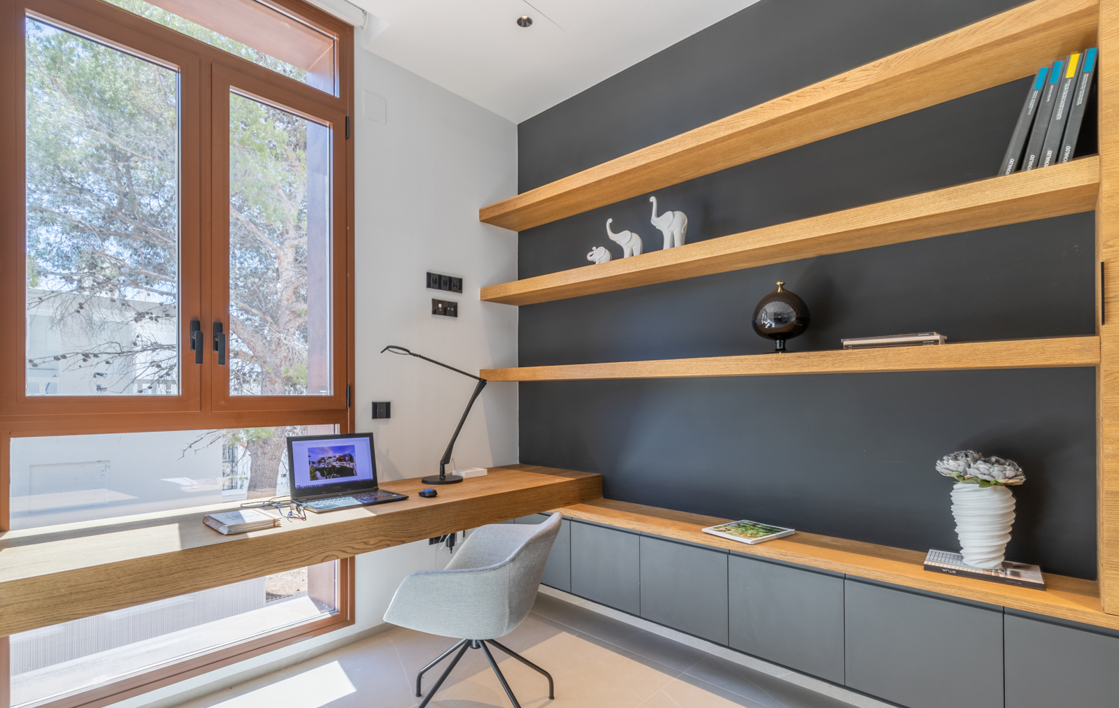 Home office met lichte houten planken en ingebouwd bureau bij het raam.