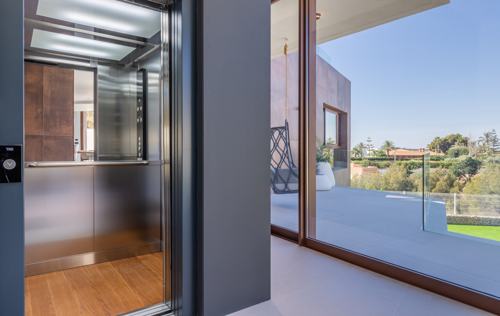 Interieur met roestvrijstalen lift en terras met uitzicht op het landschap.