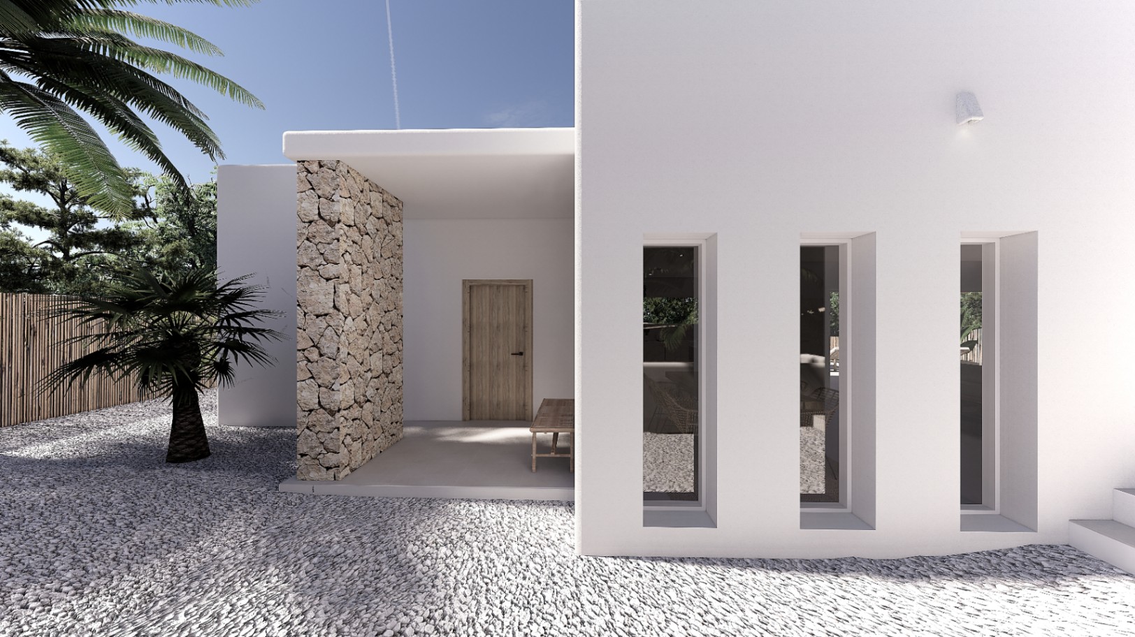 Hoofdingang met witte gevel, natuurstenen muur en verticale vensters. De oprit van wit grind en mediterrane beplanting zorgen voor een strakke, moderne uitstraling.
