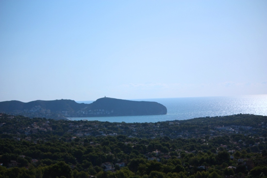 Panoramisch uitzicht vanaf de woning op de Middellandse Zee en de kaap van Moraira, omgeven door weelderige dennenbossen en woonwijken.