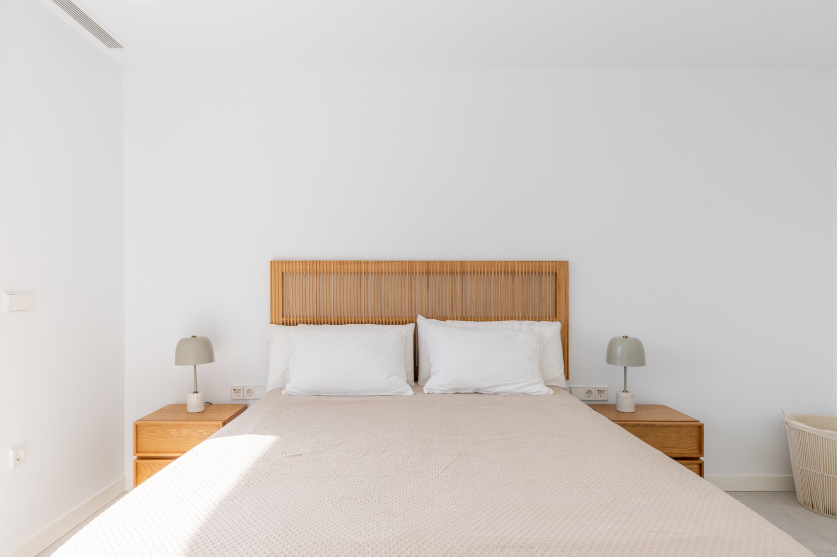 Lichte slaapkamer met houten hoofdeinde en bijpassende nachtkastjes.