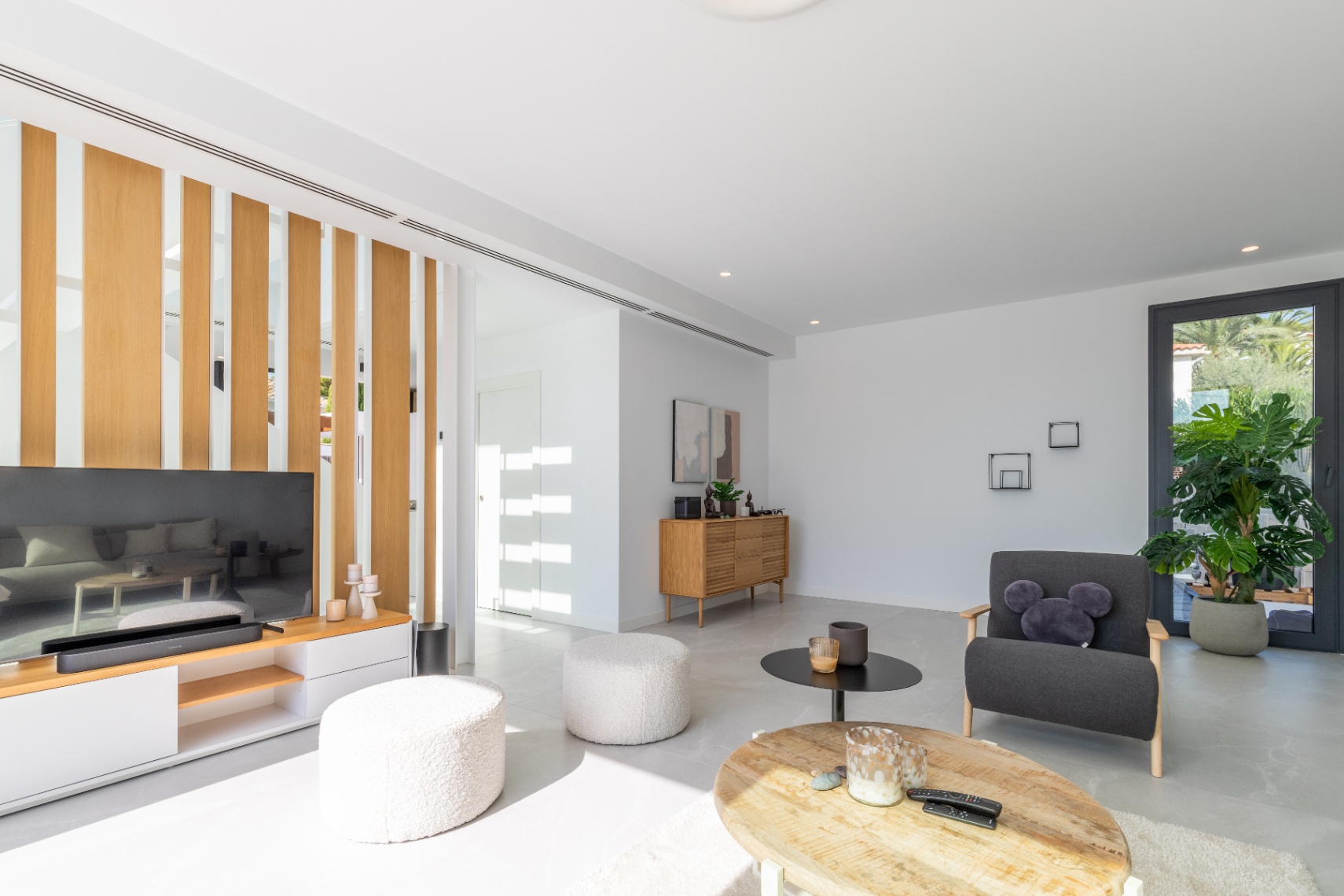 Lichte woonkamer met houten scheidingswand, modern meubilair en minimalistische designaccenten.