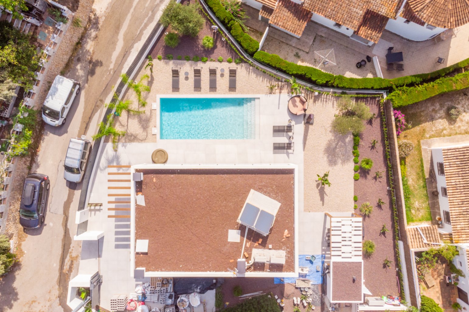 Luchtfoto van de villa met rechthoekig zwembad, zonneterras en mediterrane tuin.